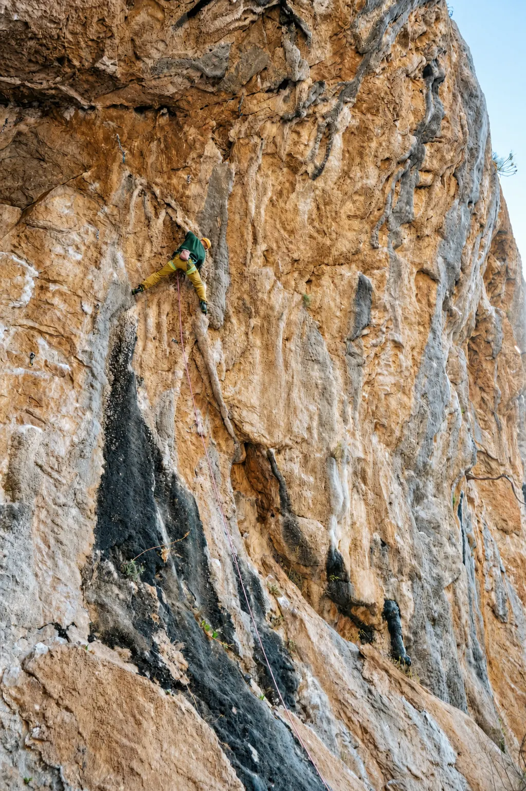 Tufa. A climber mid-route on the orange limestone this coast is famous for, at Olympos. Guides at 1:3, top rope or lead.